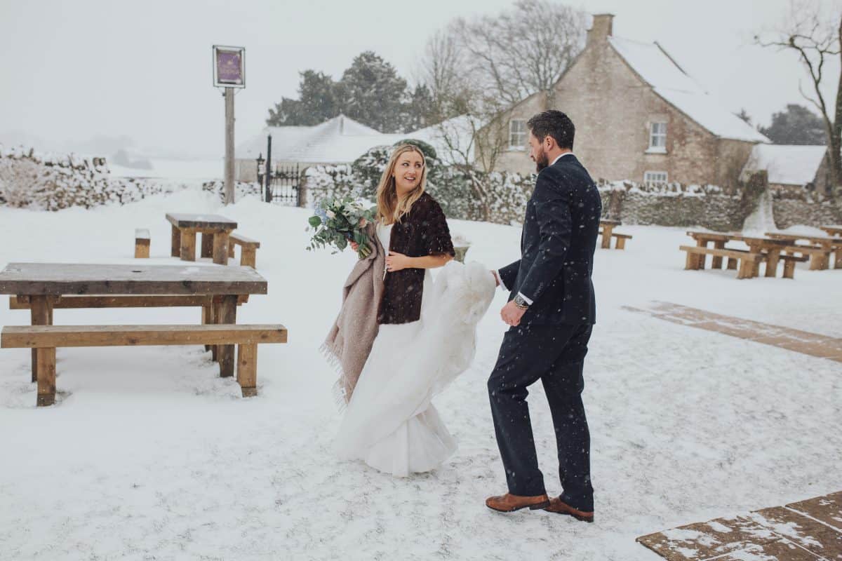 Bride and Groom walk outside in the snow at their Cotswolds wedding at the Old Lodge Minchinhampton