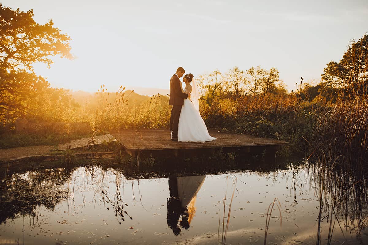 folly farm wedding couple by a pond at sunset