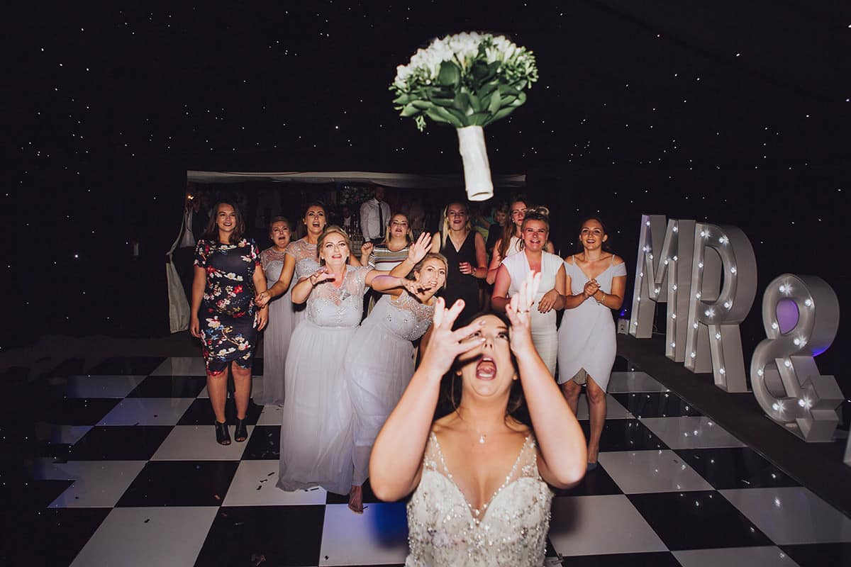 bride throwing bouquet to girls on wedding dancefloor