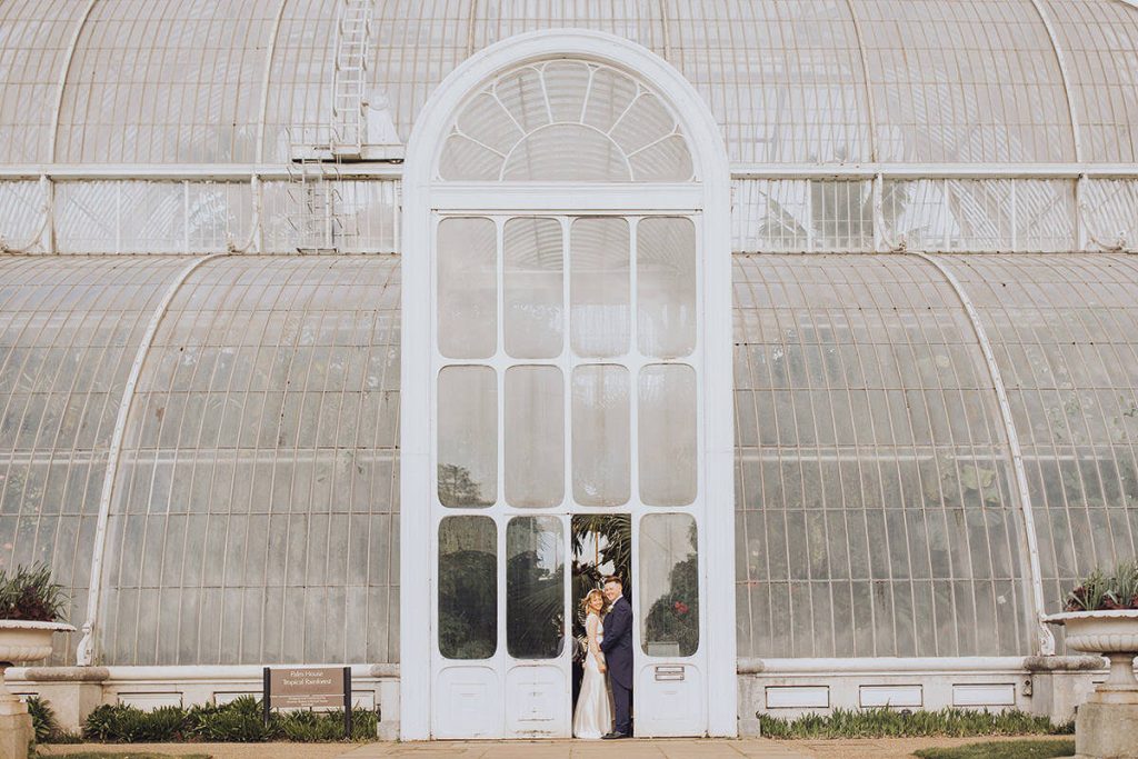 wedding couple standing outside kew gardens conservatory