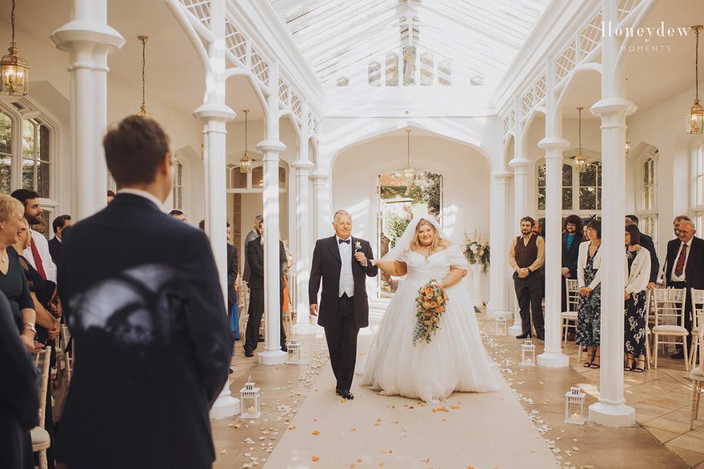 bride walking down the aisle in the orangery